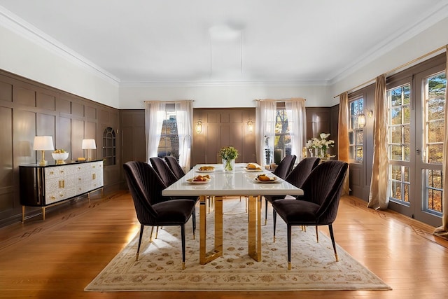 dining area featuring ornamental molding, light wood finished floors, and a decorative wall