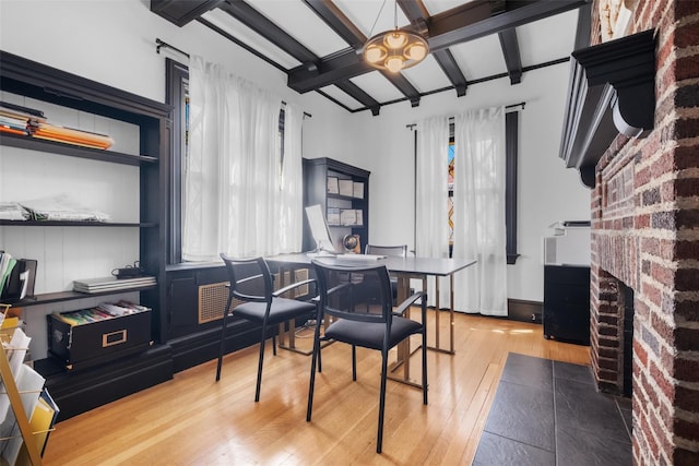 dining space with lofted ceiling with beams, a brick fireplace, and light wood-style flooring