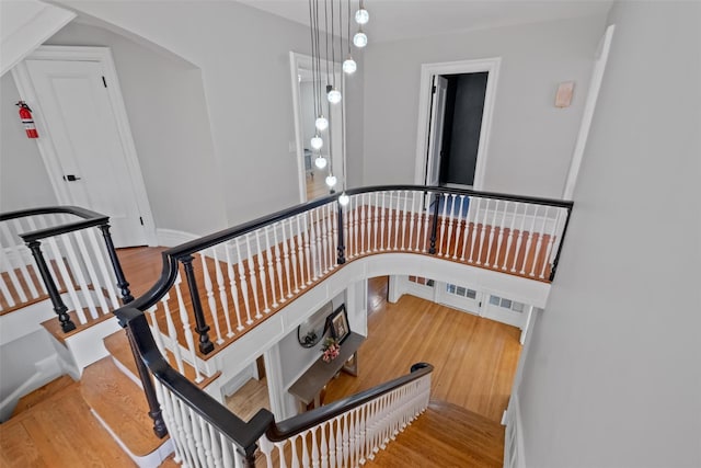 staircase featuring arched walkways, baseboards, and wood finished floors