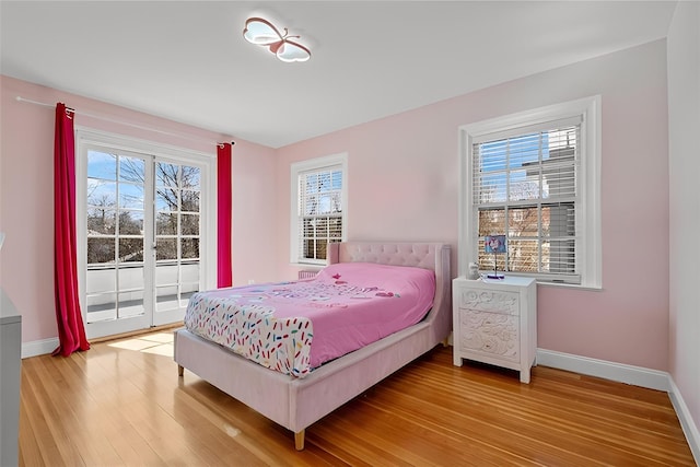 bedroom featuring multiple windows, light wood-style flooring, and baseboards