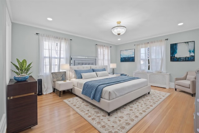 bedroom with ornamental molding, multiple windows, and wood finished floors