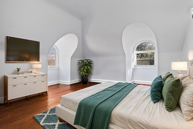 bedroom featuring vaulted ceiling, multiple windows, dark wood-style flooring, and baseboards