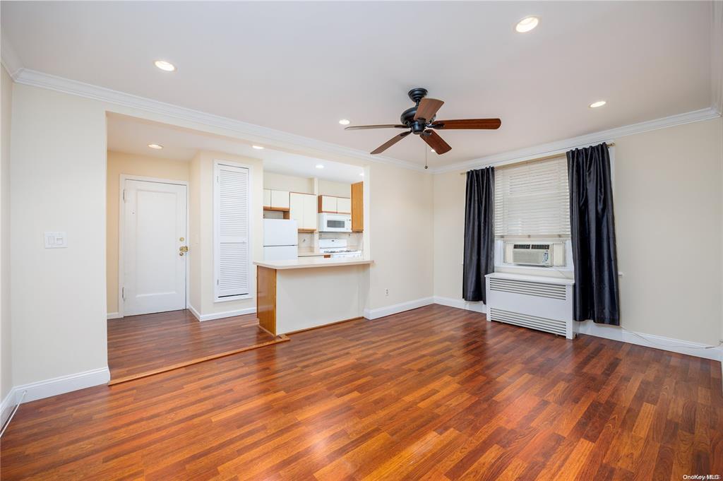 unfurnished living room featuring radiator, ceiling fan, dark hardwood / wood-style flooring, cooling unit, and ornamental molding