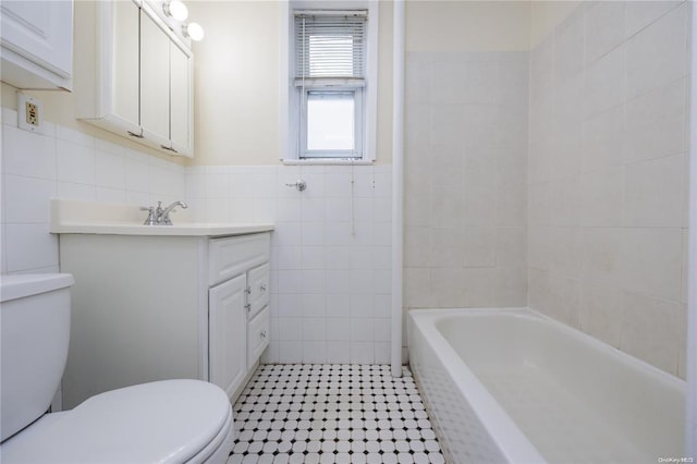 bathroom with vanity, toilet, and tile walls