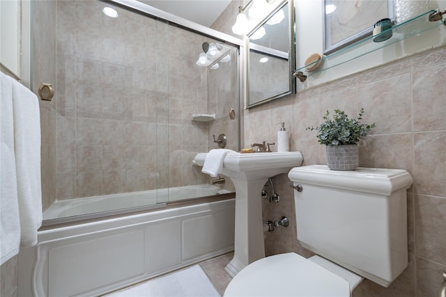 bathroom featuring shower / bath combination with glass door, tile walls, and toilet