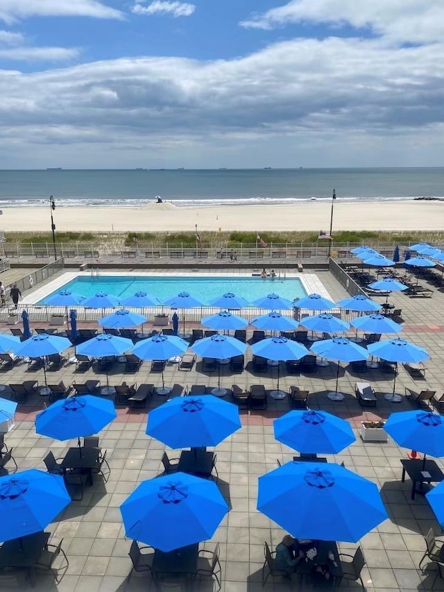 view of pool featuring a view of the beach, a patio, and a water view