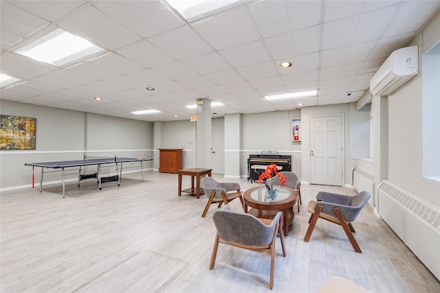 interior space featuring a paneled ceiling, radiator heating unit, light hardwood / wood-style flooring, and a wall mounted AC