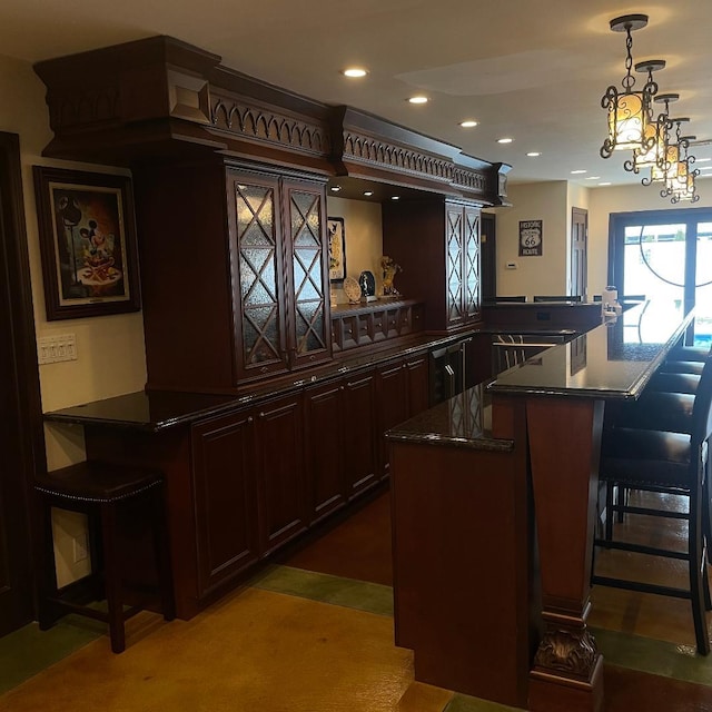 bar featuring dark brown cabinets, a notable chandelier, and hanging light fixtures