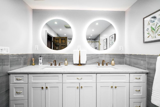 bathroom featuring double vanity, tile walls, and a sink