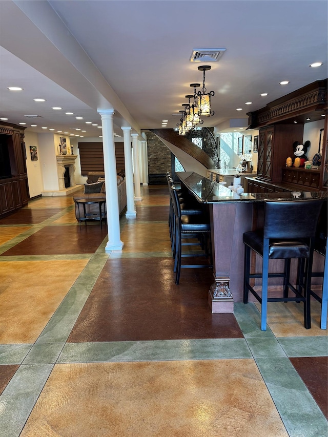 bar featuring finished concrete floors, visible vents, stairway, and ornate columns