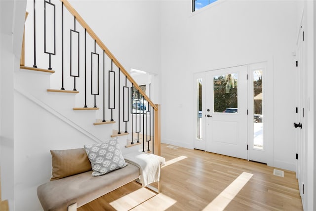 entrance foyer with a towering ceiling and light hardwood / wood-style floors