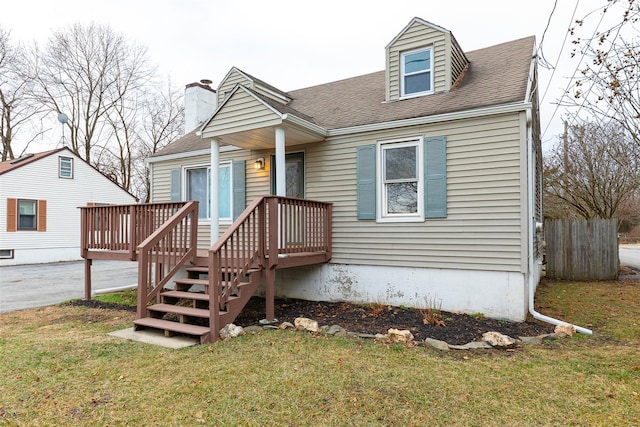 cape cod home with a front yard and a deck