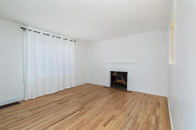 unfurnished living room featuring light hardwood / wood-style floors and a brick fireplace