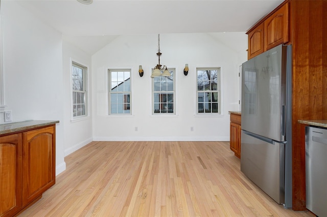 kitchen with appliances with stainless steel finishes, vaulted ceiling, decorative light fixtures, light hardwood / wood-style floors, and plenty of natural light