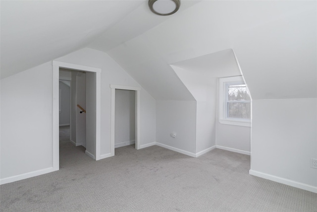 additional living space featuring light carpet and vaulted ceiling