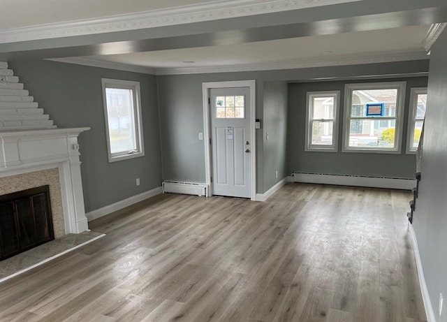 entryway featuring light wood-style floors, a baseboard radiator, crown molding, and a premium fireplace