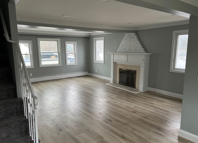 unfurnished living room featuring wood finished floors, baseboards, stairs, baseboard heating, and a glass covered fireplace