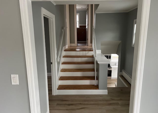 stairway featuring a baseboard radiator, crown molding, and wood finished floors