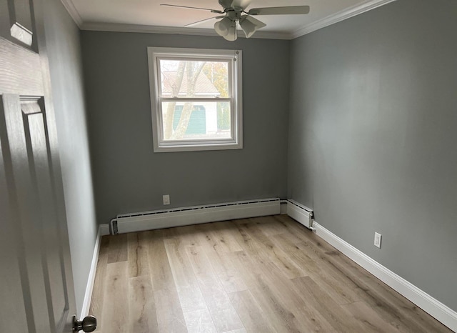 spare room with a baseboard heating unit, light wood-type flooring, baseboards, and crown molding