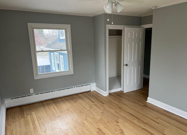 unfurnished bedroom featuring light wood-style floors, a baseboard radiator, ornamental molding, and baseboards