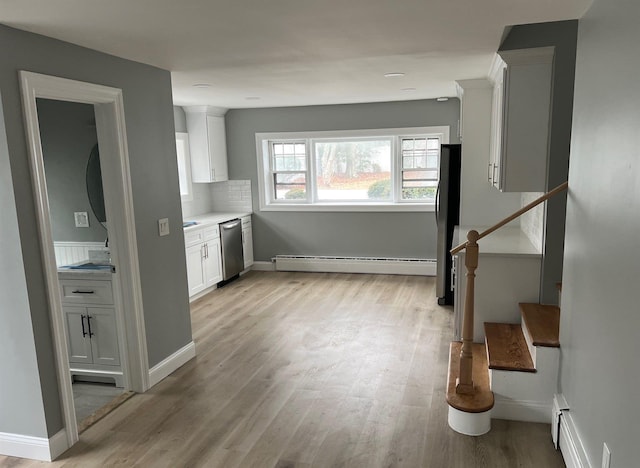 kitchen with a baseboard heating unit, white cabinetry, appliances with stainless steel finishes, and light wood finished floors