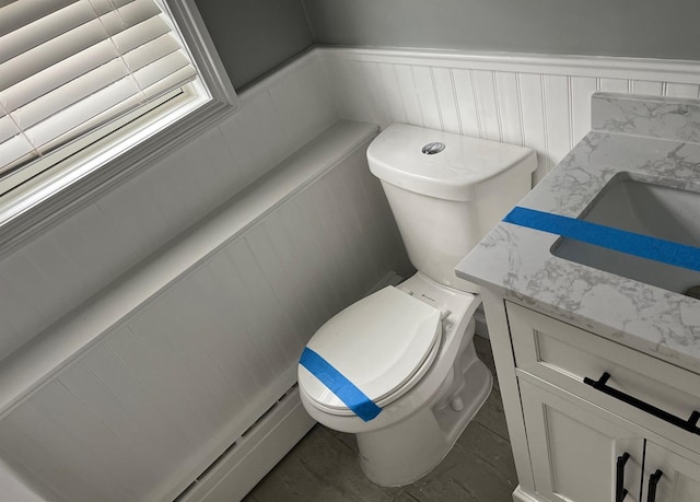 bathroom featuring a wainscoted wall, toilet, and vanity