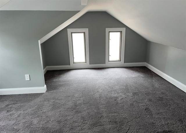 bonus room with dark colored carpet, vaulted ceiling, and baseboards