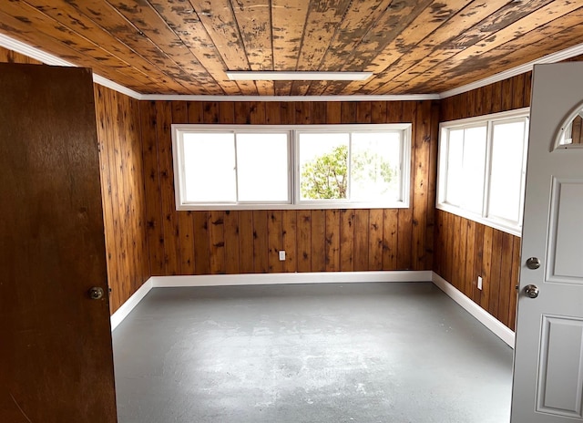 empty room featuring wood walls, wood ceiling, concrete floors, and baseboards