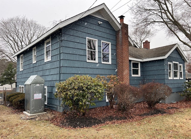 view of home's exterior featuring a chimney and fence