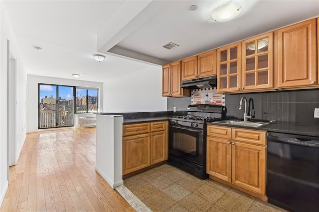 kitchen with black appliances, kitchen peninsula, sink, and tasteful backsplash