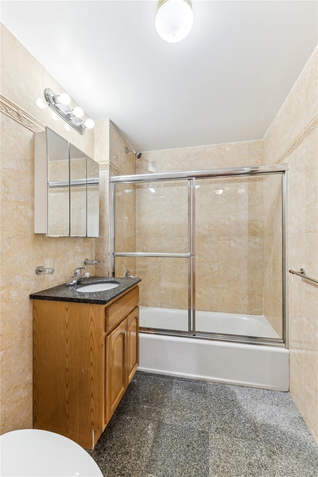 full bathroom featuring toilet, vanity, tile walls, and shower / bath combination with glass door