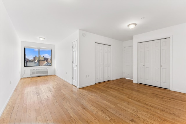 unfurnished bedroom with multiple closets and light hardwood / wood-style floors