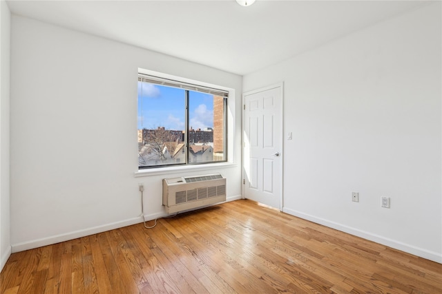 empty room with a wall unit AC and light wood-type flooring