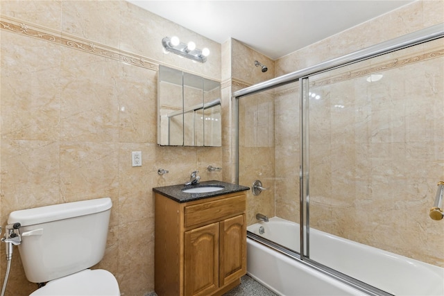 full bathroom featuring tile walls, toilet, vanity, and combined bath / shower with glass door