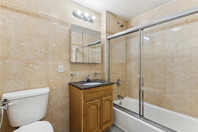 full bathroom with toilet, tile walls, vanity, and shower / bath combination with glass door