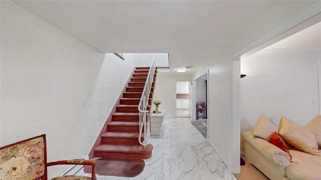 stairway featuring marble finish floor and baseboards