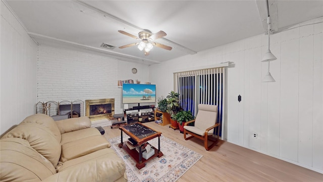 living room with a brick fireplace, light hardwood / wood-style flooring, and ceiling fan