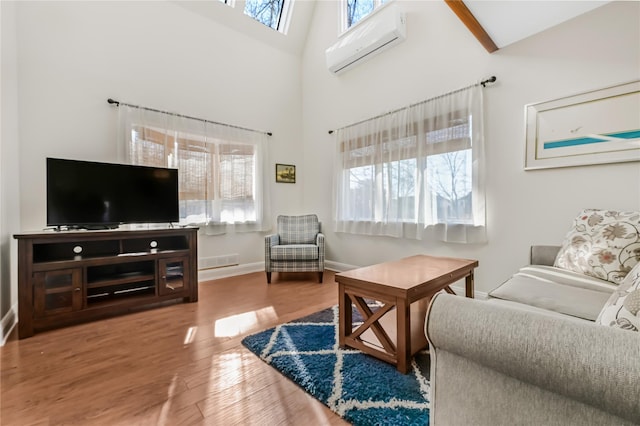 living room featuring hardwood / wood-style floors, a wealth of natural light, a wall unit AC, and a towering ceiling