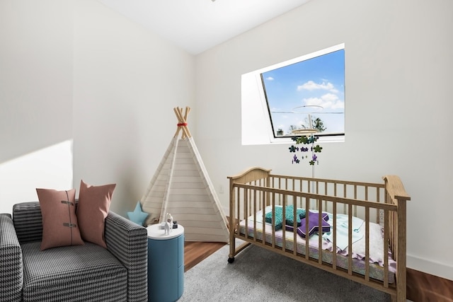 bedroom with hardwood / wood-style flooring and a crib