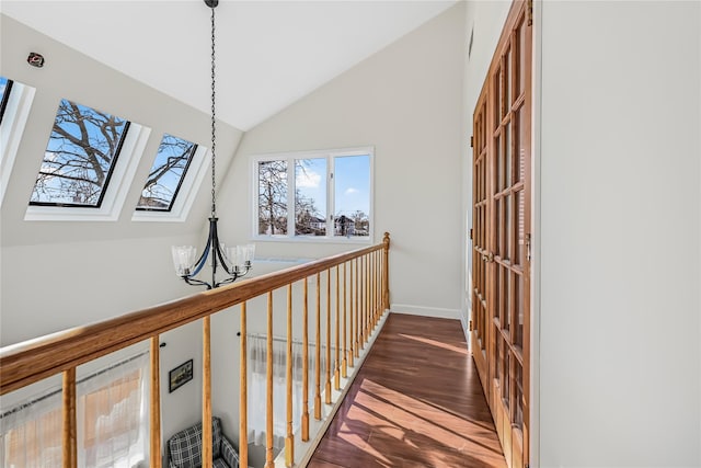 hallway featuring dark hardwood / wood-style floors, lofted ceiling with skylight, and a notable chandelier