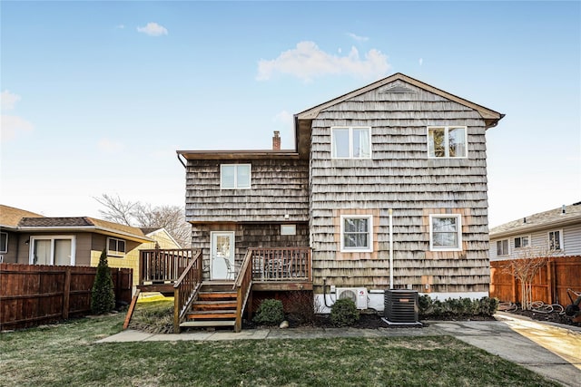 rear view of house with central AC, a wooden deck, and a yard