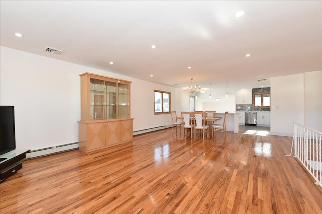 unfurnished living room featuring light wood-type flooring, a chandelier, and baseboard heating