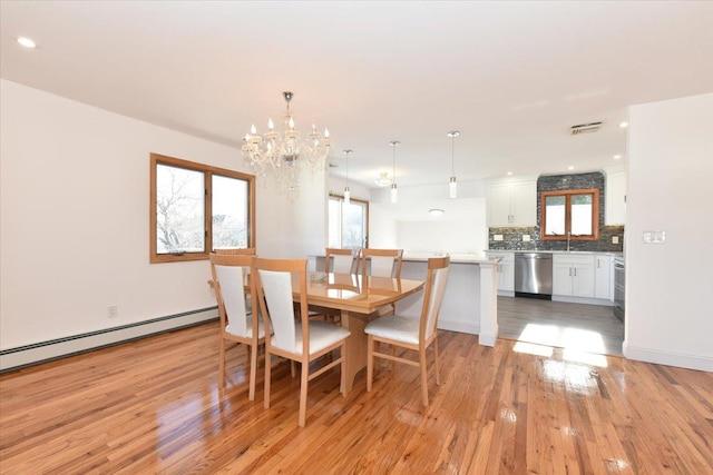 dining area featuring a notable chandelier, a baseboard radiator, sink, and light wood-type flooring