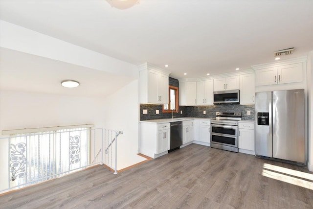 kitchen featuring tasteful backsplash, sink, white cabinets, stainless steel appliances, and light wood-type flooring