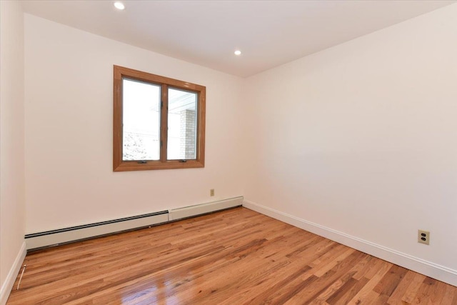 unfurnished room featuring a baseboard heating unit and light hardwood / wood-style floors