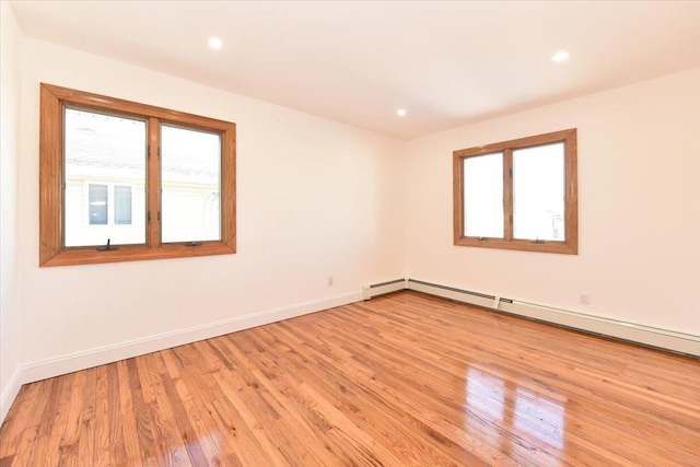 spare room with plenty of natural light, light hardwood / wood-style flooring, and a baseboard heating unit