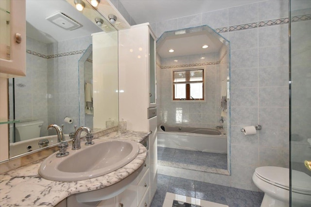 bathroom with a bathing tub, tile walls, vanity, toilet, and tile patterned floors