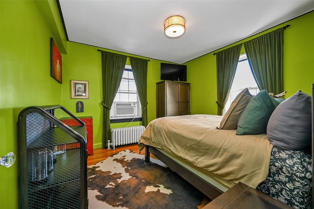 bedroom with cooling unit, radiator heating unit, and hardwood / wood-style floors