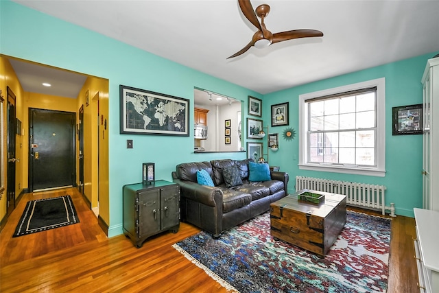 living room featuring wood-type flooring, radiator heating unit, and ceiling fan