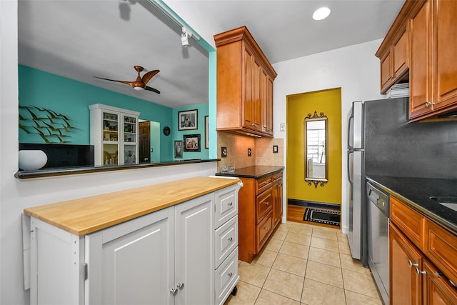 kitchen featuring stainless steel dishwasher, ceiling fan, butcher block countertops, backsplash, and light tile patterned flooring